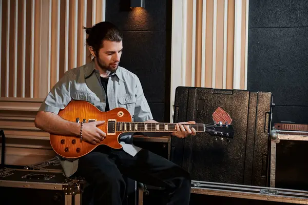 Un uomo suona appassionatamente una chitarra tra le apparecchiature musicali in uno studio di registrazione durante le prove di una band musicale. — Foto stock
