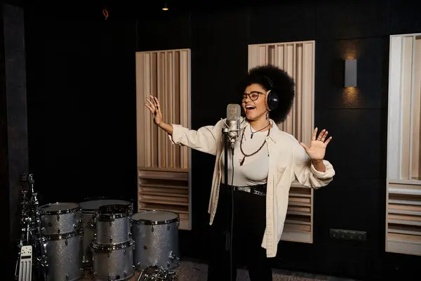 Una donna canta appassionatamente in un microfono in uno studio di registrazione durante le prove di una band musicale. — Foto stock