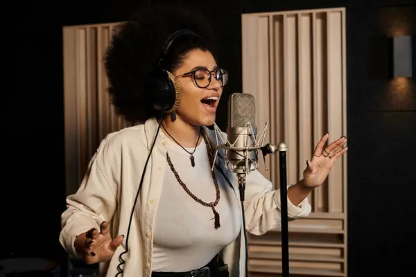 Une femme chante passionnément dans un micro d'un studio d'enregistrement lors d'une répétition d'un groupe de musique. — Photo de stock
