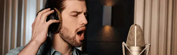 Un uomo canta appassionatamente in un microfono durante le prove di una banda musicale in uno studio di registrazione. — Foto stock