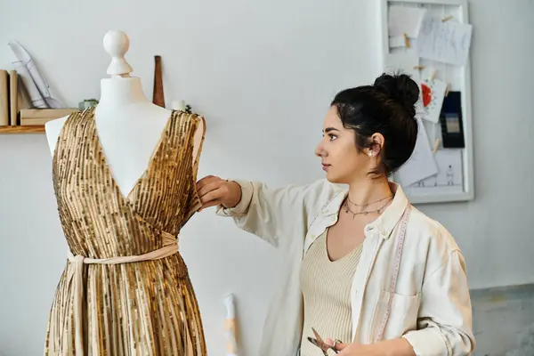 A woman in casual attire stands near a dress on a mannequin. — Stock Photo