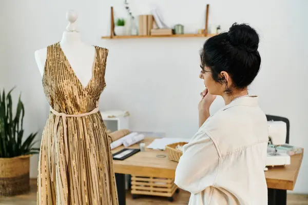 A young woman in casual attire examines a dress on a mannequin. — Stock Photo