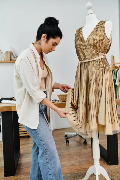 Young woman with casual attire next to mannequin displaying a dress, crafting eco-conscious fashion. — Stock Photo