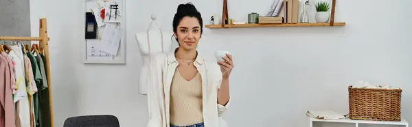 Young woman in casual attire upcycling clothes while holding a cup. — Stock Photo