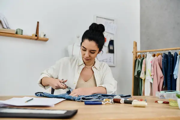 A young woman upcycles clothes, sewing and creating on a piece of cloth. — Stock Photo