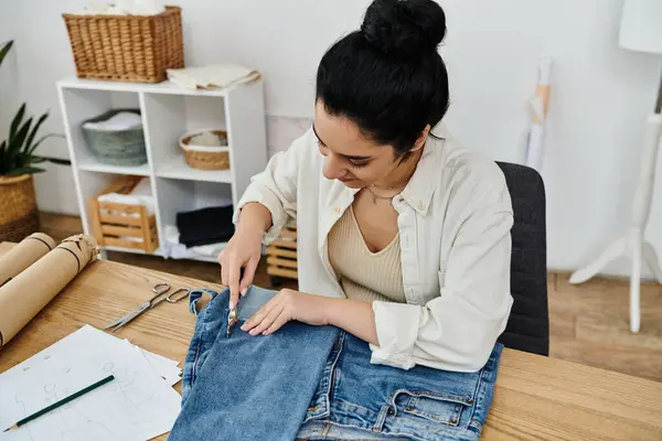 Young woman at table modifying pair of jeans, sustainable fashion concept. — Stock Photo