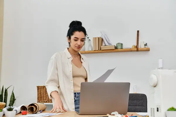 Young woman in casual attire upcycling clothes on laptop for eco-conscious fashion. — Stock Photo