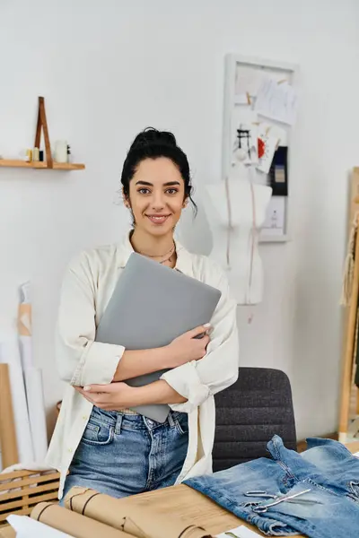 Casual woman upcycles garments holding laptop. — Stock Photo