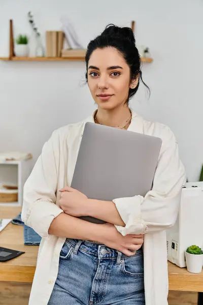 A woman standing with arms crossed, holding a laptop. — Stock Photo