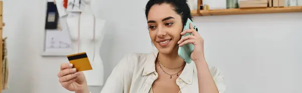 A woman holding a credit card, talking on a cell phone. — Stock Photo