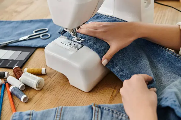A woman in casual attire upcycles jeans using a sewing machine for an eco-friendly project. — Stock Photo