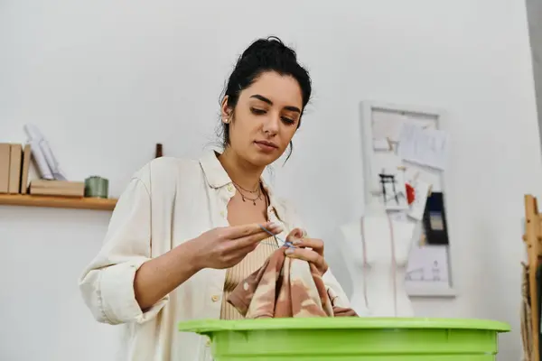 A young woman upcycles her clothes by putting them in a green basin. — Stock Photo