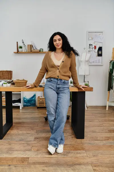 Young woman in casual attire standing in front of a wooden table, upcycling her clothes for eco-friendly purposes. — Stock Photo