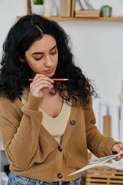 Eine Frau in lässiger Kleidung bringt Kleidung auf Vordermann und schreibt mit einem Bleistift auf Papier. — Stockfoto