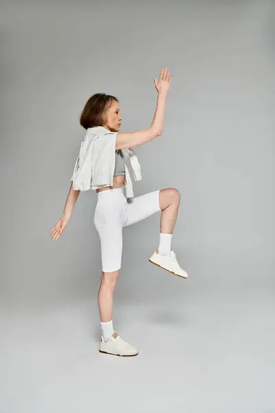 Eine reife attraktive Frau in weißen Shorts und weißem Tank-Top posiert aktiv und übt. — Stockfoto