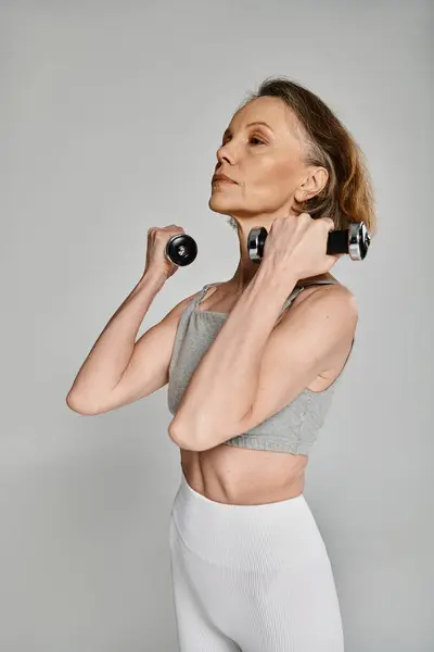 Fit woman in active wear holding dumbbells with focus and determination. — Stock Photo