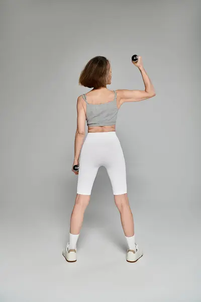 Mulher segurando halteres, exibindo força e postura. — Fotografia de Stock