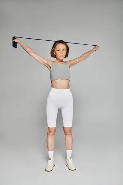 Mature woman in comfy attire exercises with resistance band. — Stock Photo