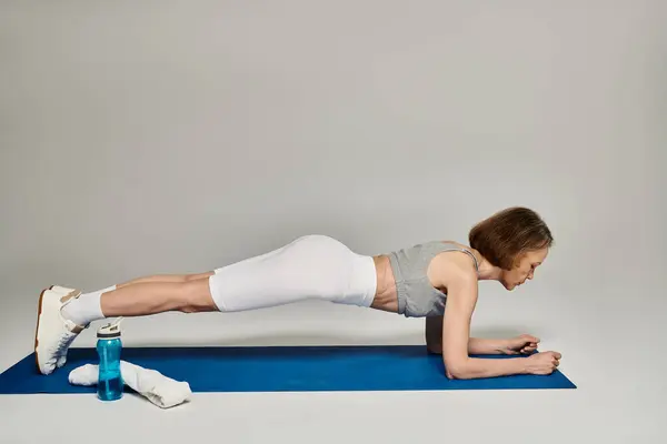 A woman planking on a blue mat. — Stock Photo