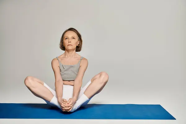 Mulher madura em ioga posar no tapete azul. — Fotografia de Stock