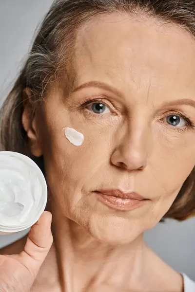 Una donna applica la crema sul suo viso con cura e attenzione. — Foto stock