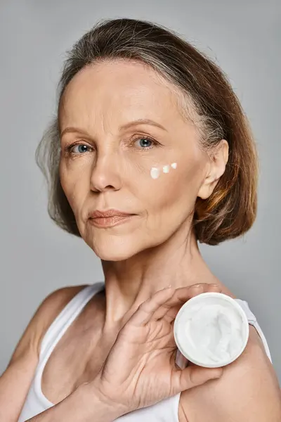 Woman in comfortable attire actively applying cream to her face. — Stock Photo