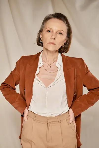 Uma mulher madura e atraente em uma jaqueta marrom e exercícios de calças bronzeadas ativamente. — Fotografia de Stock