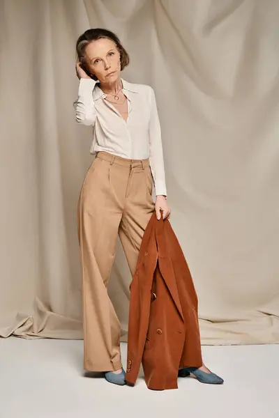 Femme élégante en chemise blanche et pantalon bronzé frappant une pose. — Photo de stock