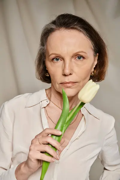 Frau im weißen Hemd hält anmutig Tulpe in der Hand. — Stockfoto