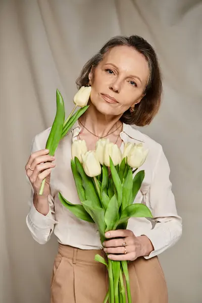 Mulher madura alegremente segurando um buquê de tulipas brancas. — Fotografia de Stock