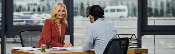 Mujer madura se involucra en una conversación con un hombre durante la entrevista de trabajo. - foto de stock