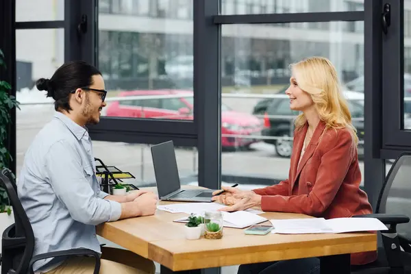 Man and woman engaging in discussion at a desk in an office setting. — Stock Photo