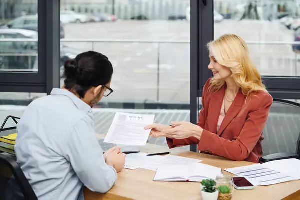 Una mujer y un hombre conversan en un escritorio. - foto de stock