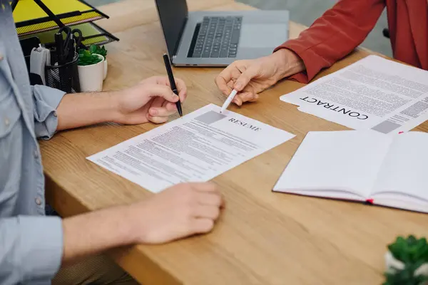 Due persone a un tavolo, che firmano un documento durante un colloquio di lavoro. — Foto stock