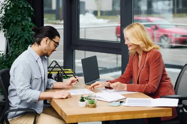 Un hombre y una mujer participan en una entrevista de trabajo en una mesa en una oficina. - foto de stock
