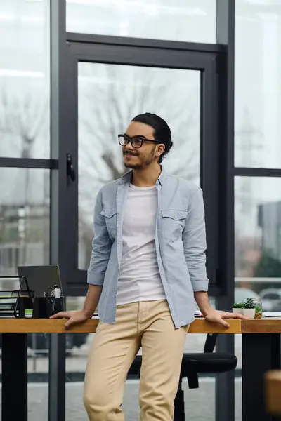 Um homem de pé confiantemente em uma mesa elegante em um escritório moderno. — Fotografia de Stock