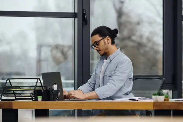 A man deeply focused on his laptop while seated at a desk. — Stock Photo