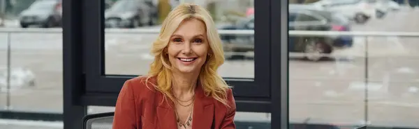 Una mujer sonriente sentada en una mesa. - foto de stock