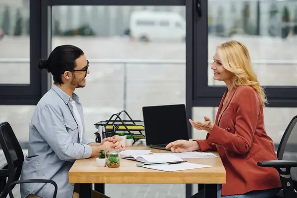 Um homem e uma mulher envolvidos em uma conversa em uma mesa no escritório. — Fotografia de Stock