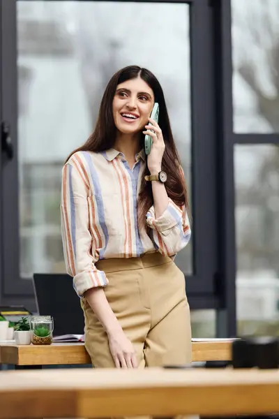 Une femme engagée dans une conversation téléphonique dans un bureau occupé. — Photo de stock