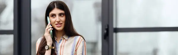 Eine Frau chattet mit einem Handy vor einem Fenster. — Stockfoto