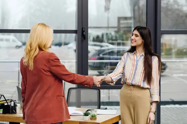 Duas mulheres apertando as mãos em um escritório, selando um acordo. — Fotografia de Stock
