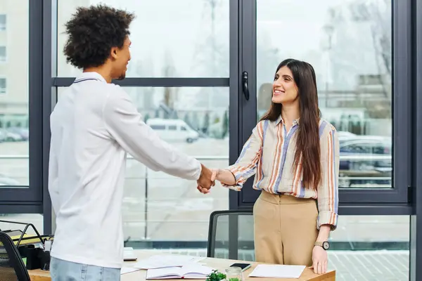 A man and woman shaking hands in an office setting. — Stock Photo