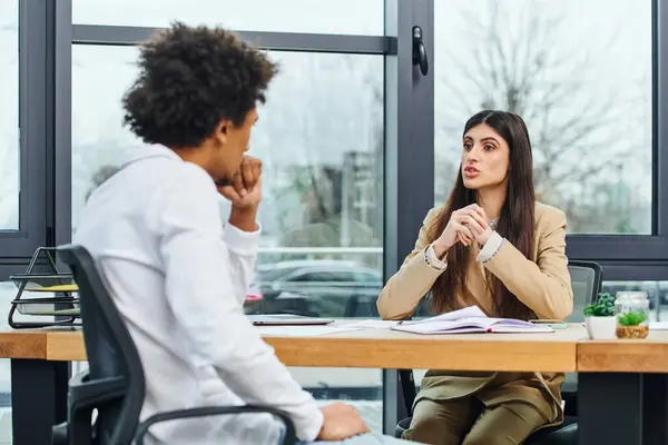 Un hombre y una mujer conversando en un escritorio. - foto de stock