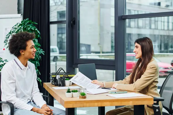 Professional man and woman discuss at desk in modern office setting. — Stock Photo