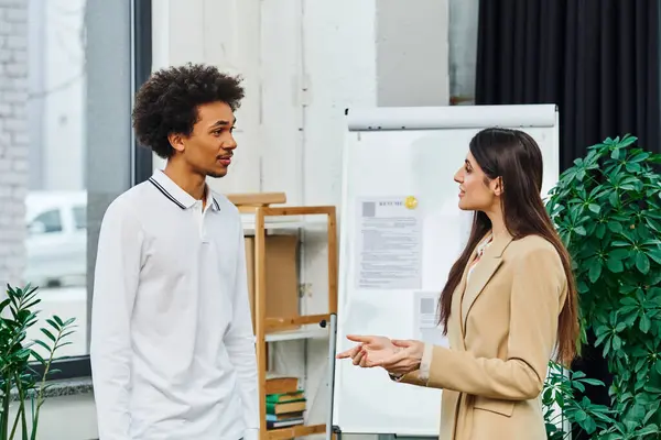 A man and a woman engage in a conversation in an office setting. — Stock Photo