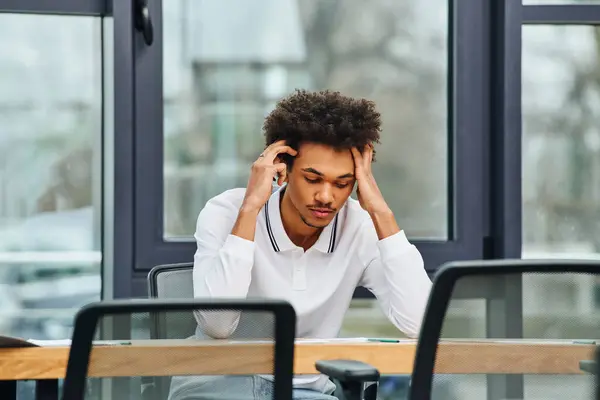 Stressed man sitting at desk, head in hands. — Stock Photo