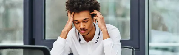 Man in distress sits at desk with head in hands. — Stock Photo