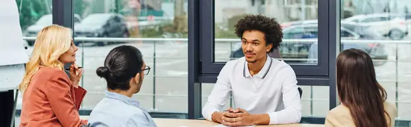 Buscadores de empleo participan en una animada discusión alrededor de la mesa de la oficina. - foto de stock