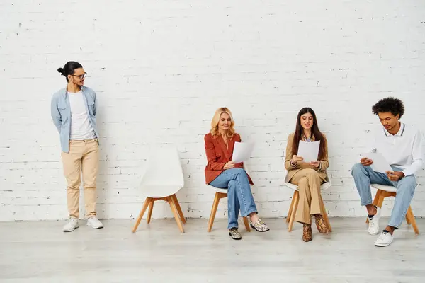 A group of people seated in front of a clean white wall. — Stock Photo